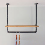 Ceiling mounted industrial bar rack with top distressed wood shelf.