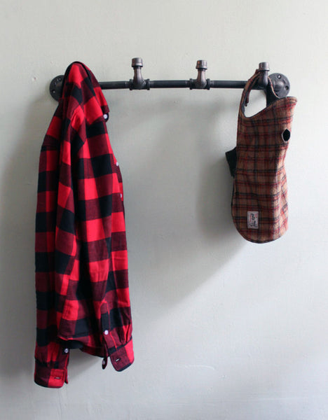 Wall mounted coat rack with a red flannel shirt and dog coat handing on it's hooks